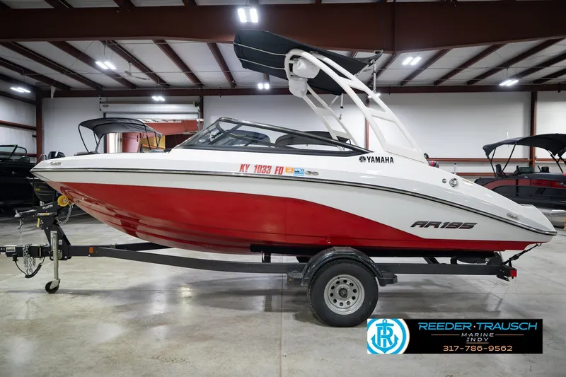 Slide: The Image of 2024 Yamaha Boats AR195 in showroom, red and white design, on trailer. - 11
