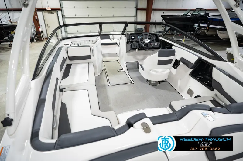 Slide: The Image of 2024 Yamaha Boats AR195 interior with sleek seating and modern dashboard in a showroom. - 15