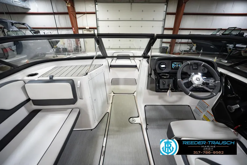 Slide: The Image of 2024 Yamaha Boats AR195 interior with modern dashboard and seating in a showroom. - 17