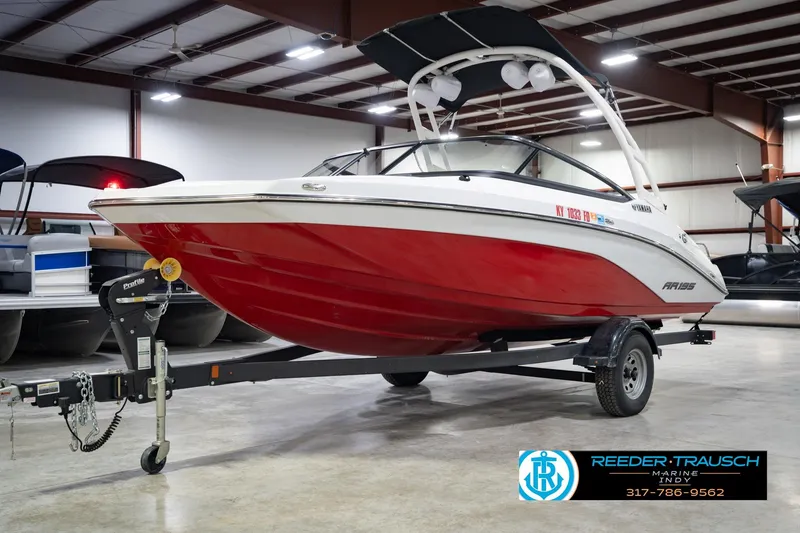 Slide: The Image of 2024 Yamaha AR195 boat in showroom, red and white design, on trailer. - 4