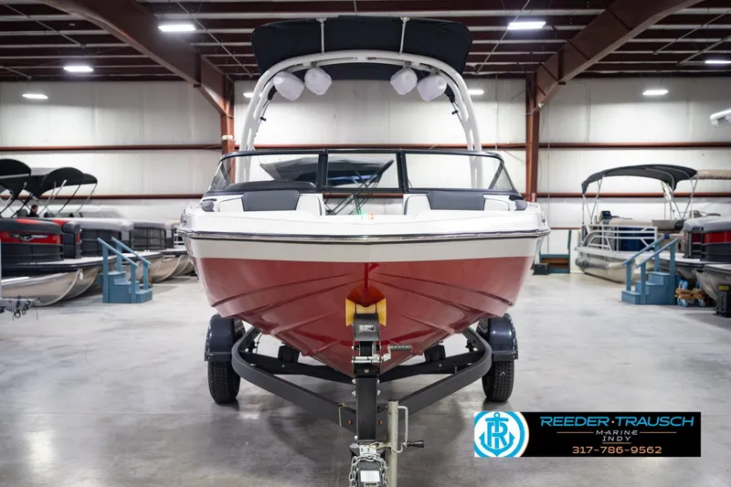 Slide: The Image of 2024 Yamaha Boats AR195 in showroom, red hull, on trailer, indoor display. - 5