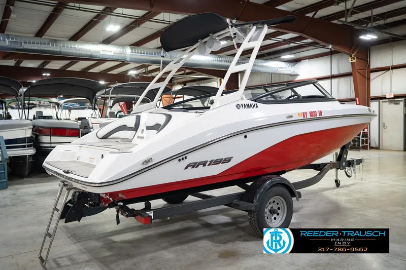 Slide: The Image of 2024 Yamaha AR195 boat in showroom, featuring sleek red and white design on trailer. - 8