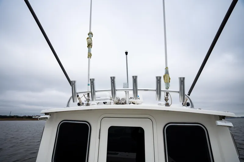 Slide: The Image of 2021 Parker 2520 XLD Sport Cabin boat with fishing rod holders on a cloudy day. - 21