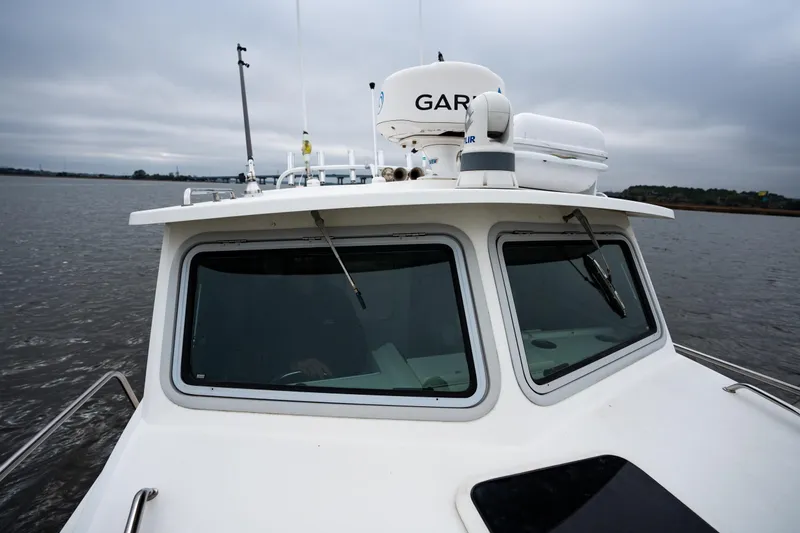 Slide: The Image of 2021 Parker 2520 XLD Sport Cabin boat on calm water under cloudy sky. - 29