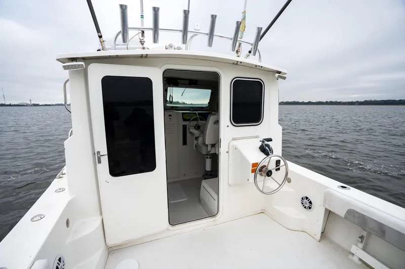 Slide: The Image of 2021 Parker 2520 XLD Sport Cabin boat on calm water, showcasing cabin entrance. - 41