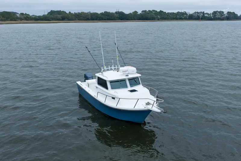 Slide: The Image of 2021 Parker 2520 XLD Sport Cabin boat on calm water, overcast sky. - 9