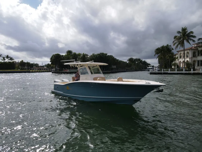 Slide: The Image of 2017 Scout 320 LXF boat on calm water with palm trees. - 15