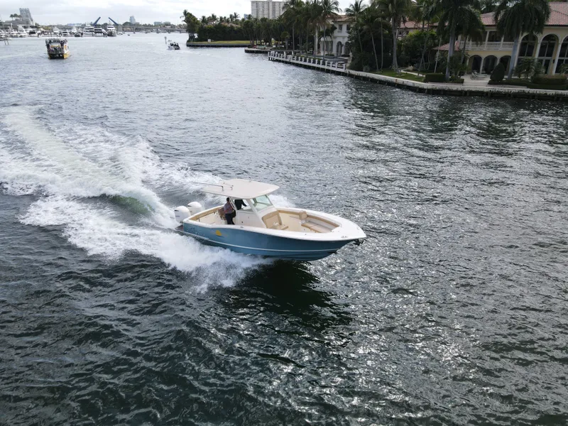 Slide: The Image of 2017 Scout 320 LXF boat on water, coastline in background. - 16