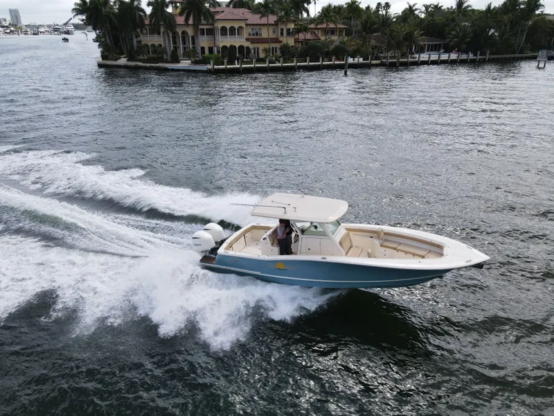 Slide: The Image of 2017 Scout 320 LXF boat cruising near waterfront villa. - 17