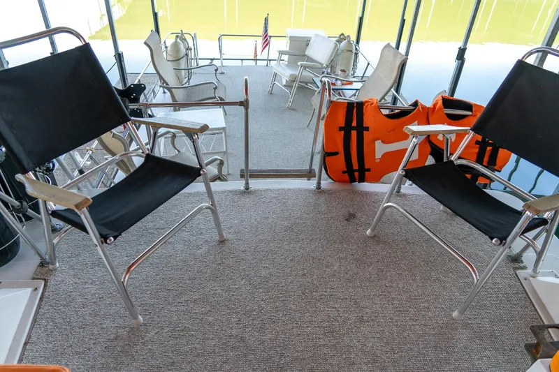 Slide: The Image of 1974 Boatel 47 Islander deck with chairs and life jackets, overlooking calm water. - 11