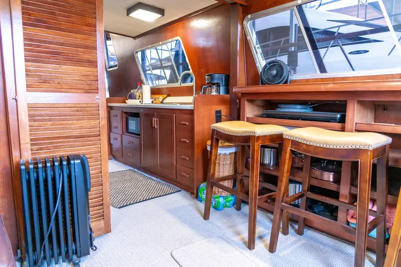 Slide: The Image of 1974 Boatel 47 Islander interior with wooden cabinetry, bar stools, and kitchen area. - 17