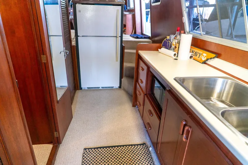 Slide: The Image of 1974 Boatel 47 Islander kitchen with wooden cabinets, sink, and refrigerator. - 19