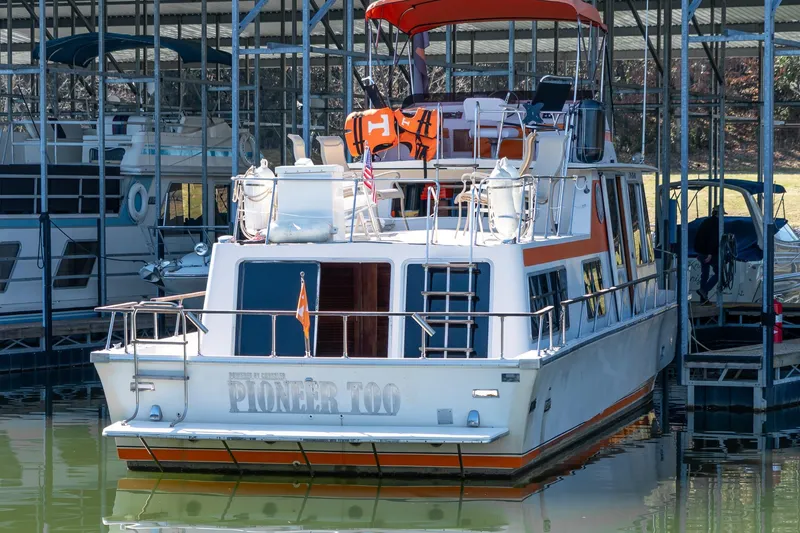 Slide: The Image of 1974 Boatel 47 Islander docked in marina, featuring orange accents and upper deck seating. - 3