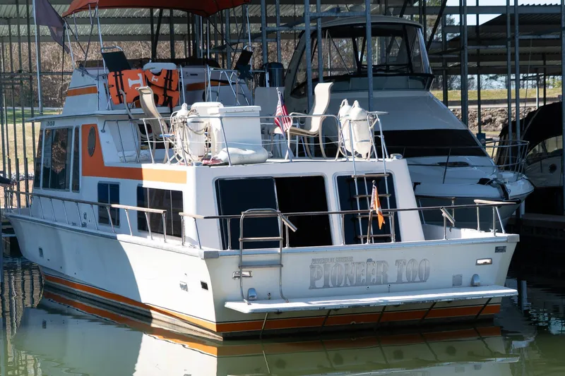Slide: The Image of 1974 Boatel 47 Islander docked in marina, featuring orange accents and outdoor seating. - 4