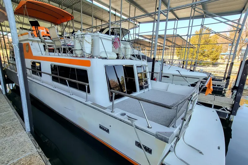 Slide: The Image of 1974 Boatel 47 Islander docked in a covered marina, featuring orange accents. - 5
