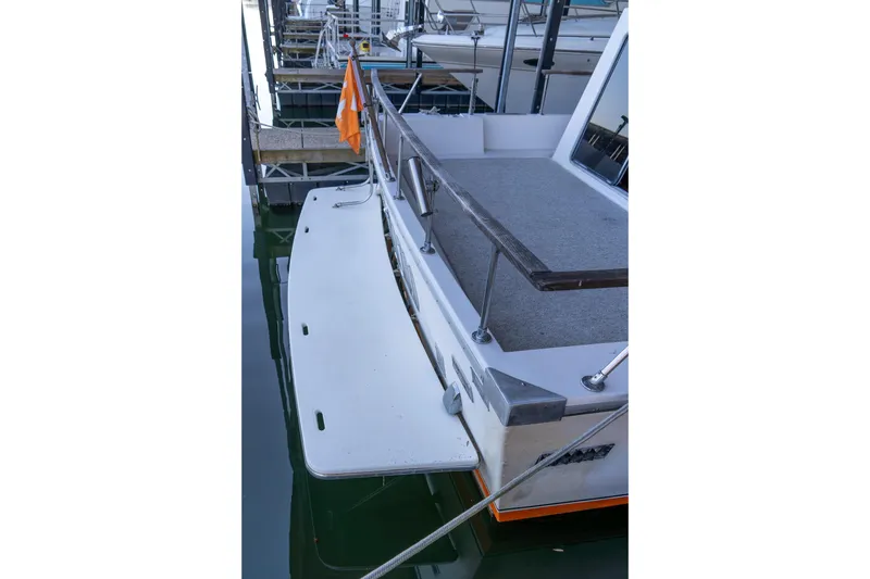 Slide: The Image of 1974 Boatel 47 Islander boat docked, featuring a spacious deck and railing. - 8