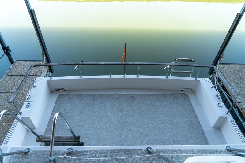 Slide: The Image of 1974 Boatel 47 Islander boat deck with railing, docked on calm water. - 9
