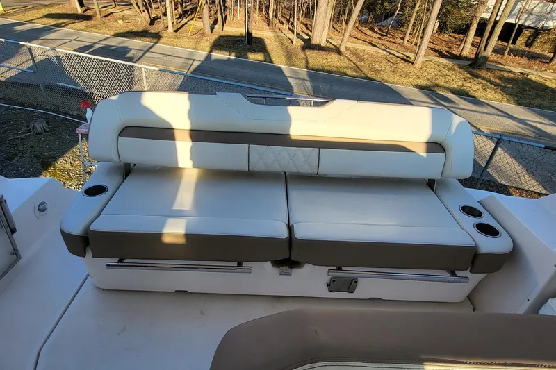 Slide: The Image of 2018 Regal 35 Sport Coupe boat seating with cup holders, in a sunny outdoor setting. - 19