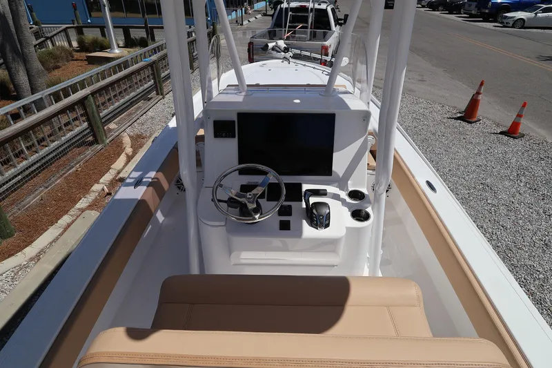 Slide: The Image of 2026 Contender 26 Bay boat console with steering wheel and controls, parked on gravel. - 12