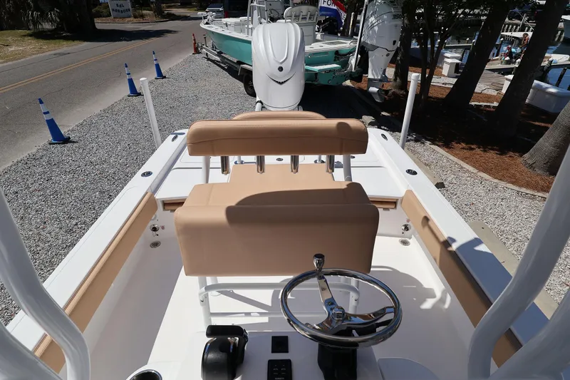 Slide: The Image of 2026 Contender 26 Bay boat interior with steering wheel and seating, parked on gravel. - 22