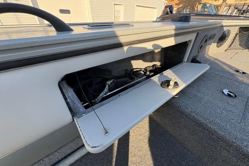 Slide: The Image of 2005 Lund 2025 Pro-V LE boat storage compartment with open hatch, revealing interior equipment. - 24