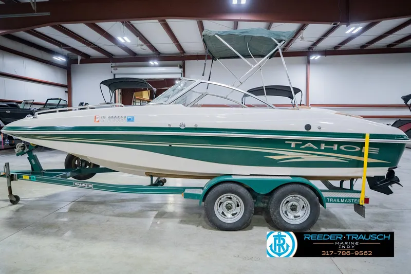 Slide: The Image of 2004 Tahoe 204 boat on trailer in indoor showroom, green and white design. - 11