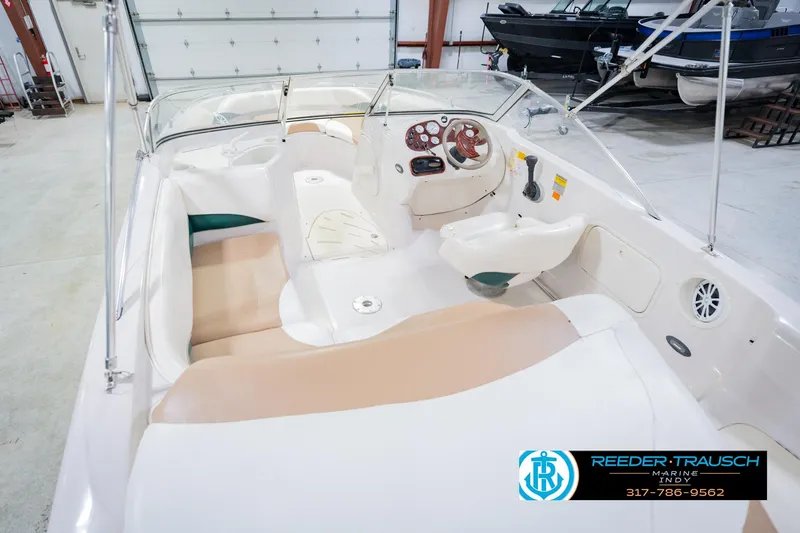 Slide: The Image of 2004 Tahoe 204 boat interior with beige seating and steering console in a showroom. - 15