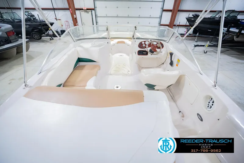 Slide: The Image of 2004 Tahoe 204 boat interior with beige seating and steering wheel in a showroom. - 16
