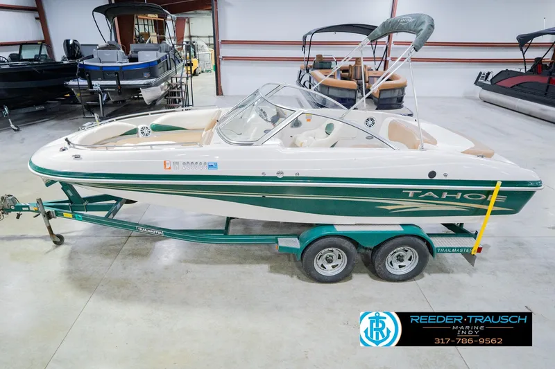 The Image of 2004 Tahoe 204 boat on trailer in indoor showroom, green and white design. - 2