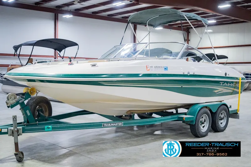 Slide: The Image of 2004 Tahoe 204 boat on trailer in indoor showroom, green and white design. - 4
