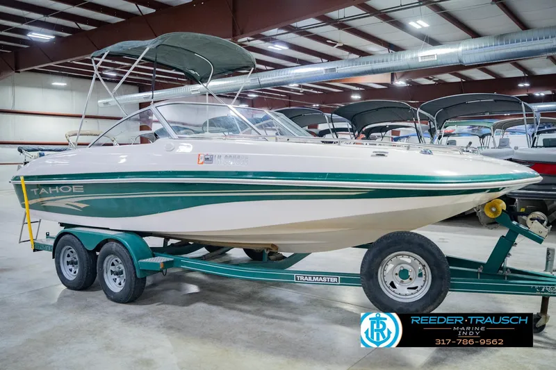 Slide: The Image of 2004 Tahoe 204 boat on trailer in indoor showroom, green and white design. - 6