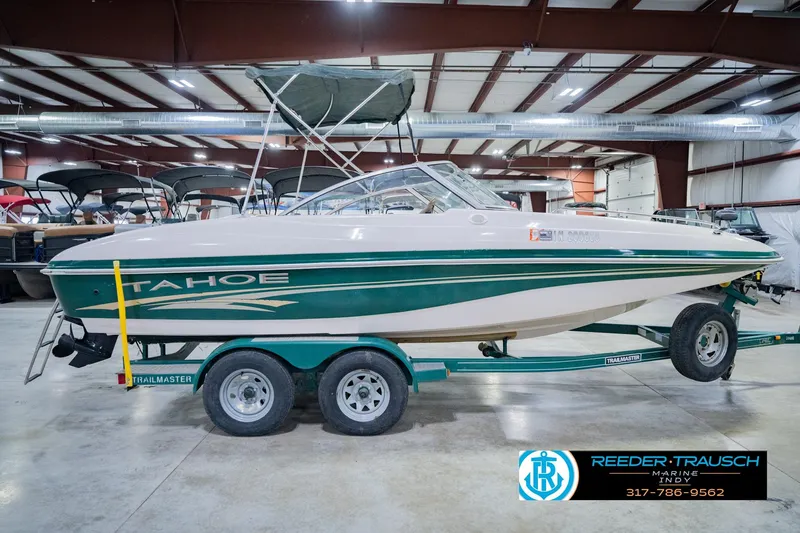 Slide: The Image of 2004 Tahoe 204 boat on trailer in indoor showroom, green and white design. - 7