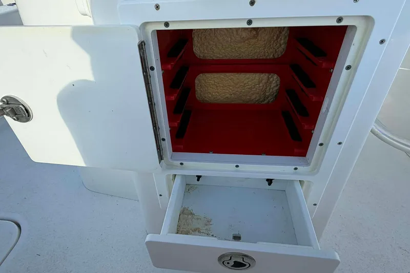 Slide: The Image of Open storage compartment on a 2021 Blazer Bay 2420 boat, featuring red interior shelving. - 12