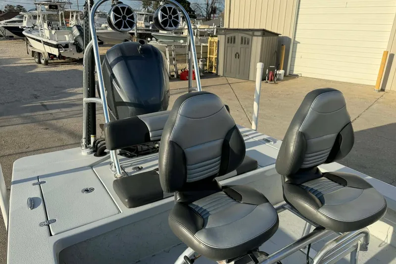 Slide: The Image of 2021 Blazer Bay 2420 boat interior with dual seats and motor, parked outdoors. - 18