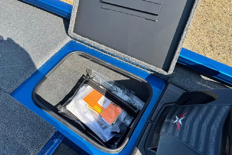 Slide: The Image of Open storage compartment in 2026 Vexus Defender 181 boat, containing documents and accessories. - 14