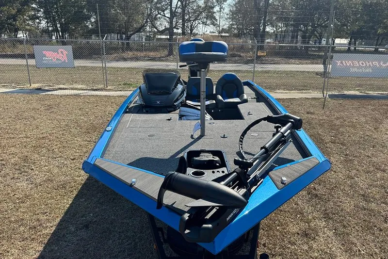 Slide: The Image of 2026 Vexus Defender 181 boat, blue exterior, parked on grass near a fence. - 9