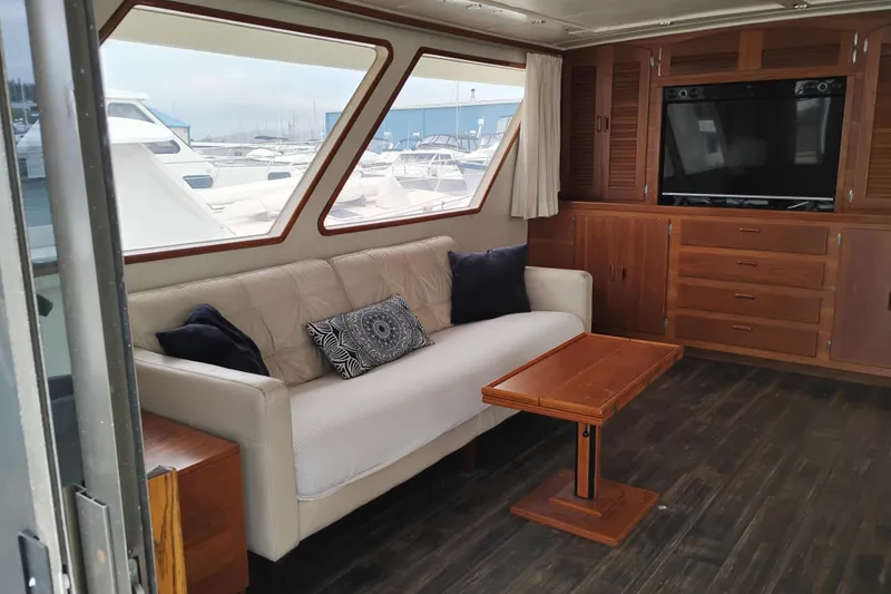 Slide: The Image of Luxurious 1977 Custom International Offshore 65 yacht interior with sofa, wooden table, and large windows. - 19