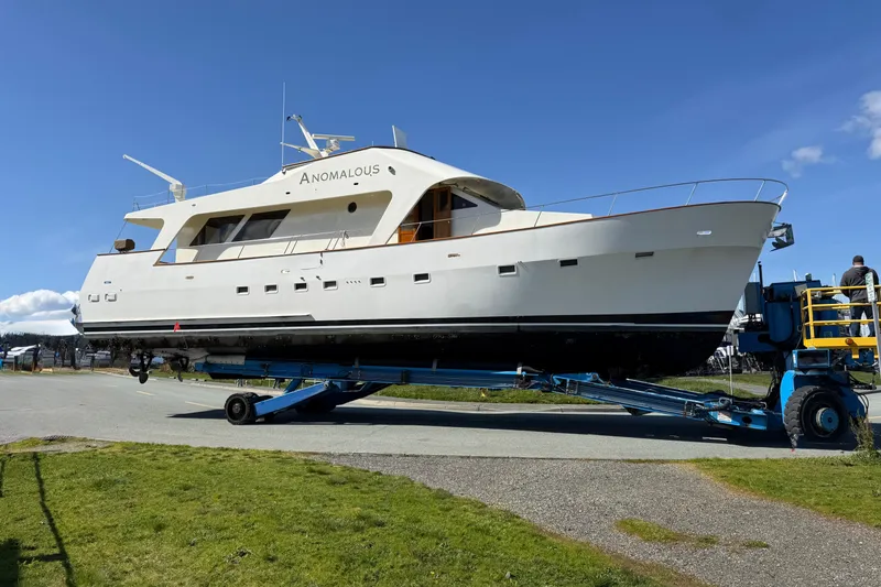 Slide: The Image of 1977 Custom International Offshore 65 yacht on transport trailer under clear blue sky. - 2