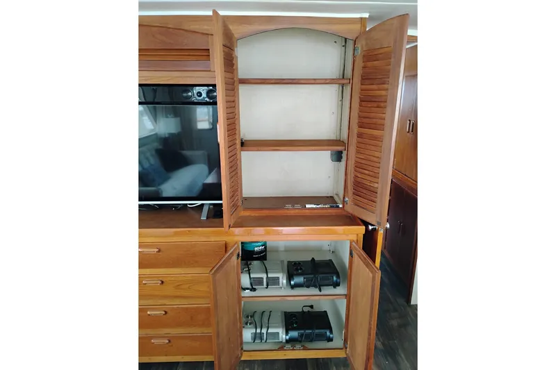 Slide: The Image of Wooden cabinet with open doors, shelves, and equipment inside, aboard a 1977 Custom International Offshore 65. - 26