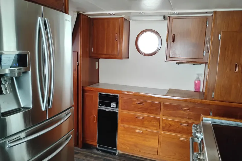 Slide: The Image of Kitchen area of 1977 Custom International Offshore 65 yacht with wooden cabinets and stainless steel appliances. - 29