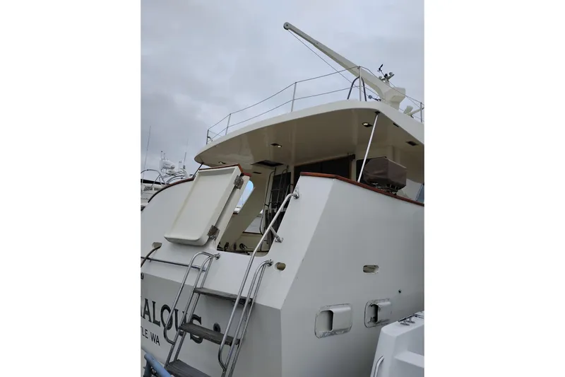 Slide: The Image of 1977 Custom International Offshore 65 yacht with open hatch and ladder, docked under cloudy skies. - 3