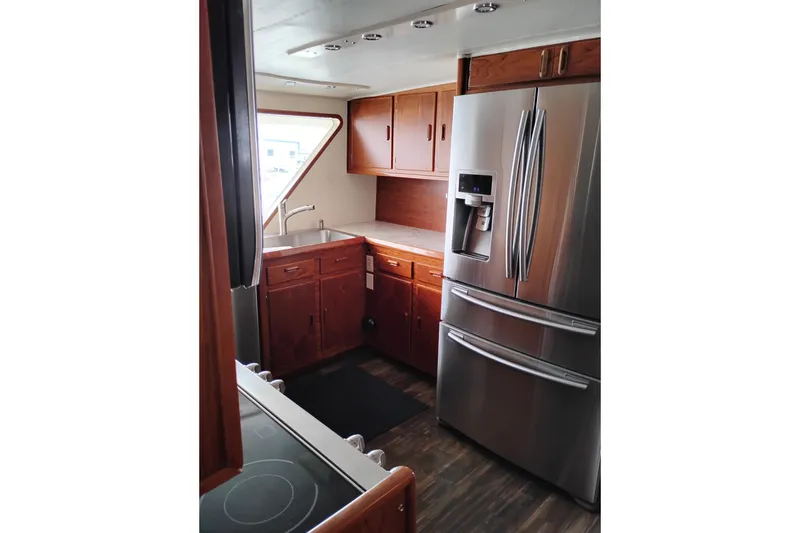 Slide: The Image of 1977 Custom International Offshore 65 yacht kitchen with stainless steel fridge and wooden cabinets. - 30