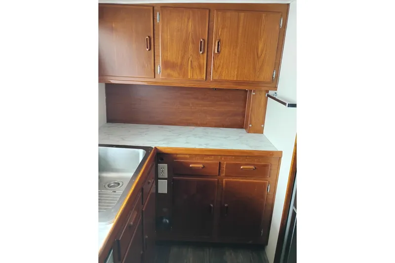 Slide: The Image of 1977 Custom International Offshore 65 yacht kitchen with wooden cabinets and marble countertop. - 34
