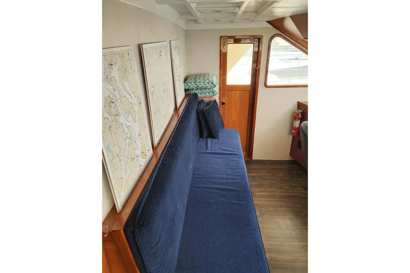 Slide: The Image of Interior of 1977 Custom International Offshore 65 with blue seating and nautical maps. - 38