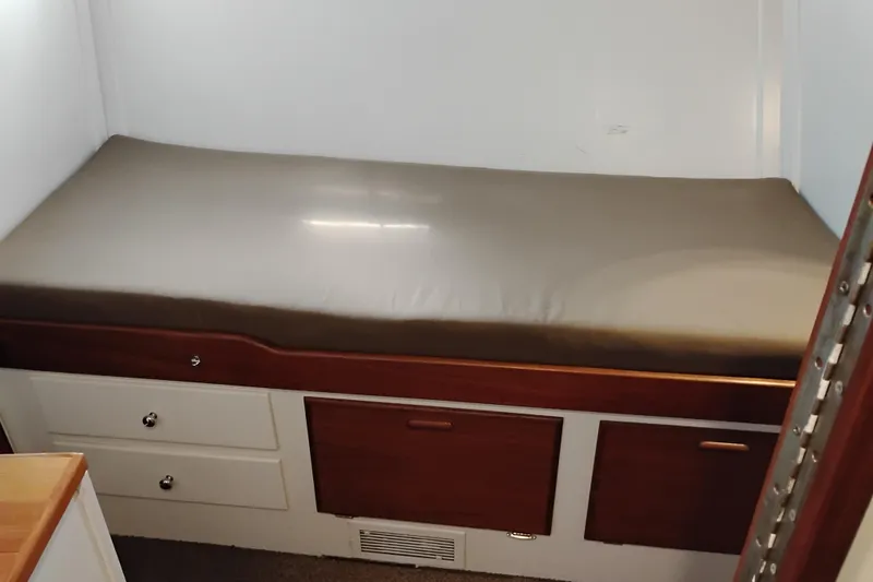Slide: The Image of Interior cabin of 1977 Custom International Offshore 65 with a cushioned bed and storage drawers. - 51