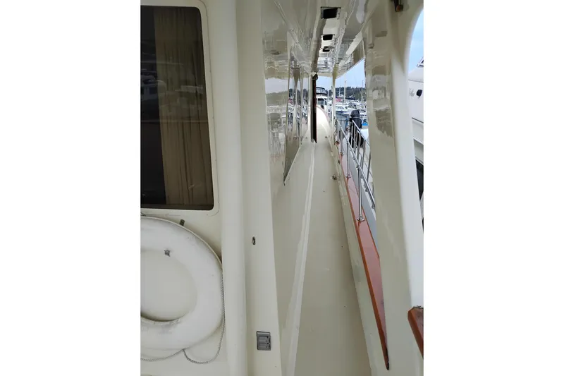 Slide: The Image of Side deck view of 1977 Custom International Offshore 65 yacht, featuring sleek design and safety railings. - 6