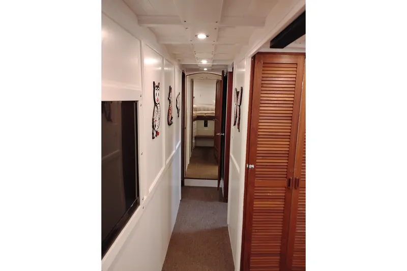 Slide: The Image of Narrow hallway inside 1977 Custom International Offshore 65 yacht, featuring wooden doors and wall decor. - 61