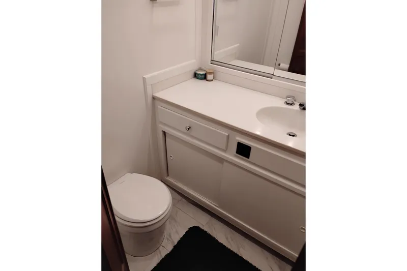 Slide: The Image of Small bathroom with white vanity and toilet on a 1977 Custom International Offshore 65. - 63