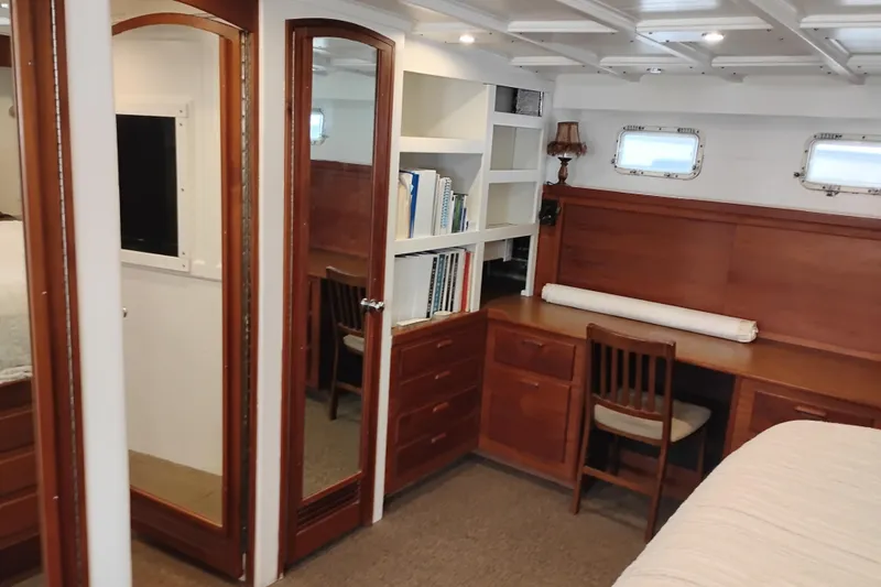 Slide: The Image of Luxurious 1977 International Offshore 65 yacht interior with wooden desk, shelves, and mirrors. - 74