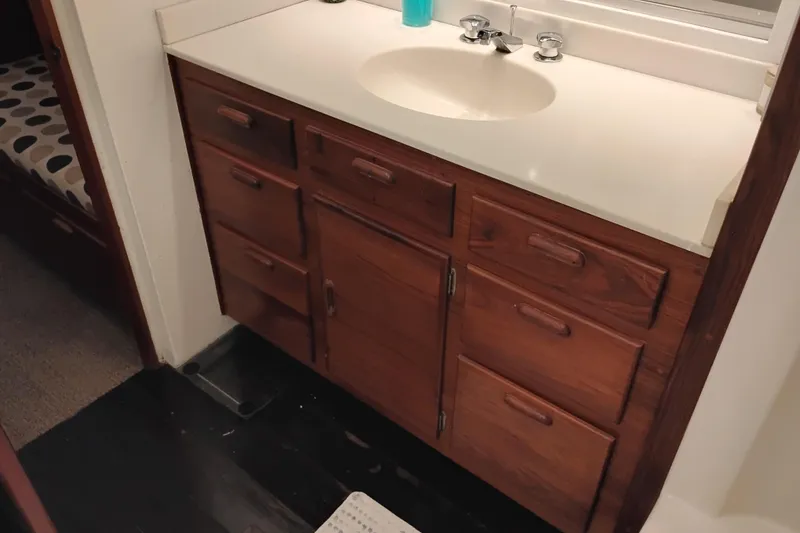 Slide: The Image of Wooden bathroom vanity with multiple drawers and a white countertop in a 1977 International Offshore 65. - 80